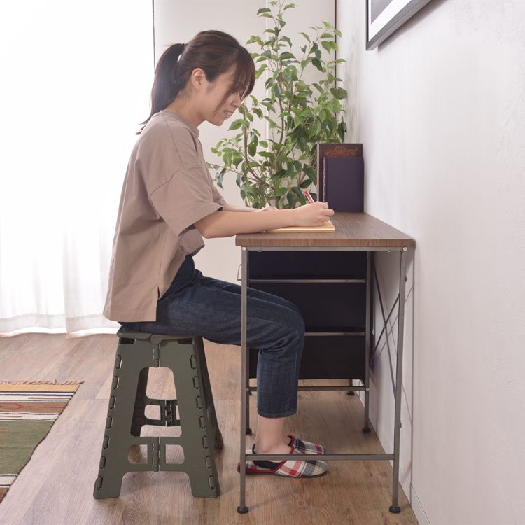 デスクで作業スツールに座って作業をする女性のイメージ写真