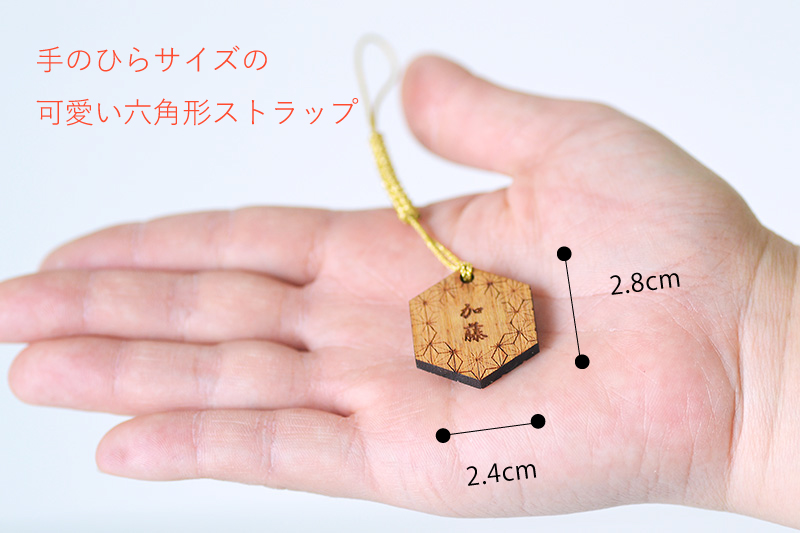 六角形の名前入りストラップのサイズを手のひらで比較する画像