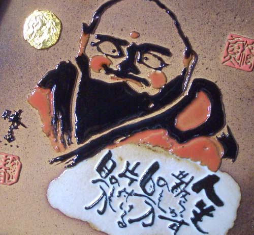 泉 椿魚）戯句斜句画陶板・箕形「人生 散らかすのも自分