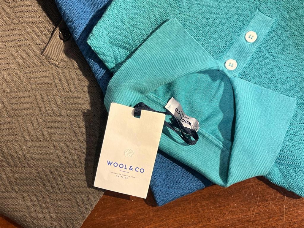 三色のWOOL&COニットポロを重ね、襟・前立て・ボタンの質感を強調したトップ画像。上品な立体編みとカラー展開をひと目で把握できる構図。